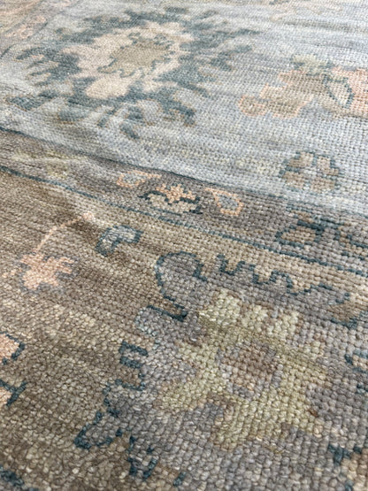 Juliet hand-knotted wool Turkish Oushak rug in light blue with tan border and pink, teal, and blue