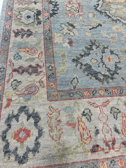Kennedy Turkish Oushak rug, hand-knotted wool with a light blue base, ivory border, and navy, light gold, light green, and raspberry accents