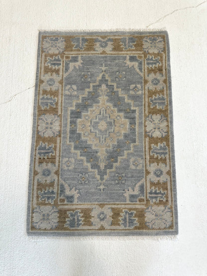 Susie hand-knotted wool modern Oushak rug in soft gray-blue with brown border and sage green and tan tones