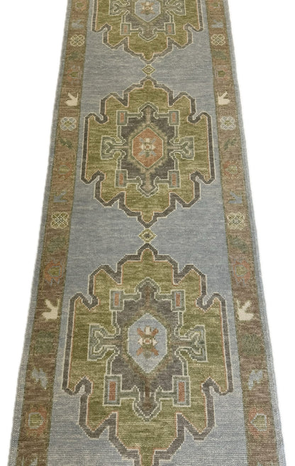 Blue and green turkish hand-knotted runner rug with geometric pattern on a plain background