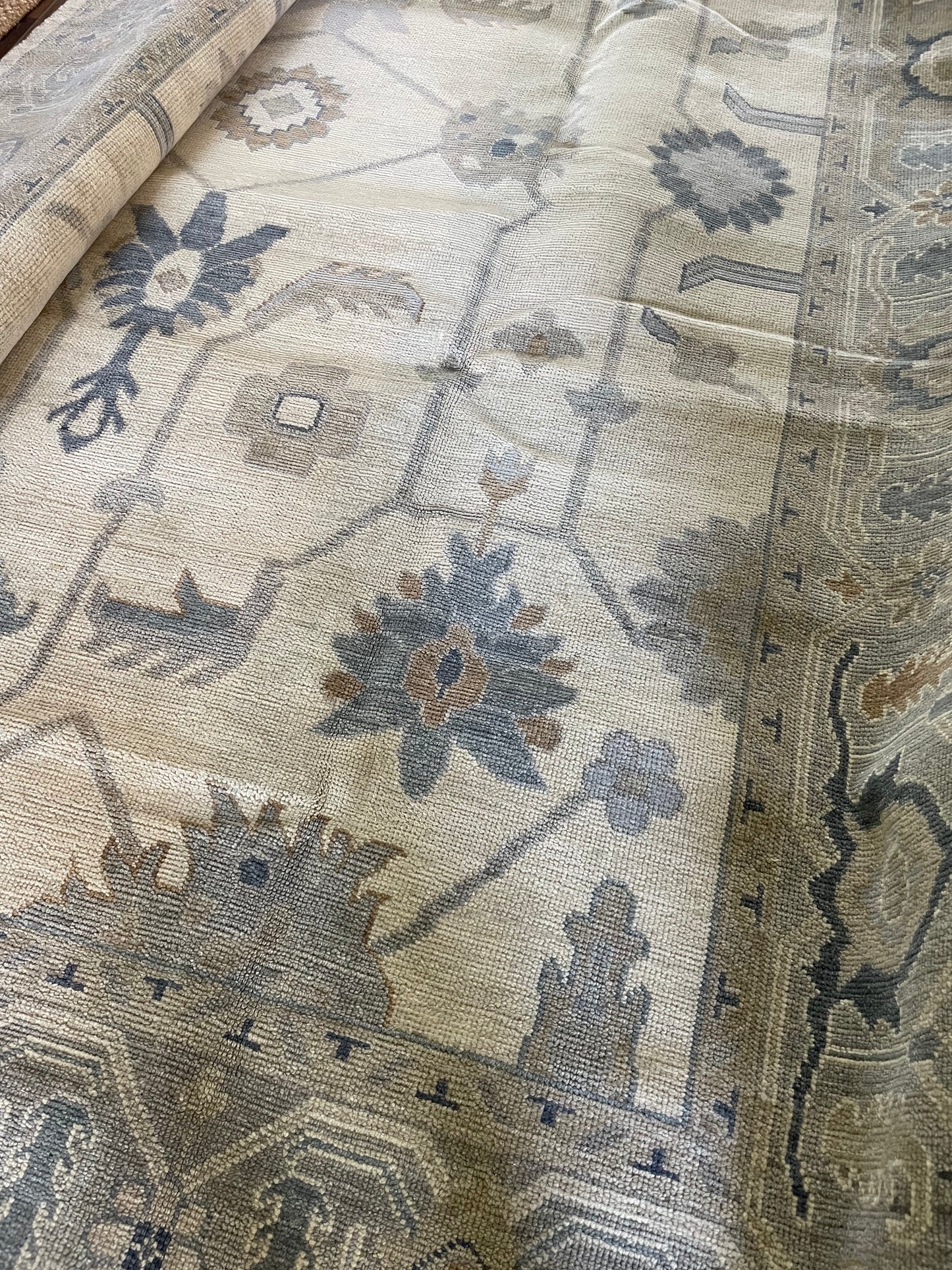 A close-up view of Emory Modern Oushak  geometric patterned rug featuring a cream foundation with hints of gray, warm tan, and blue.