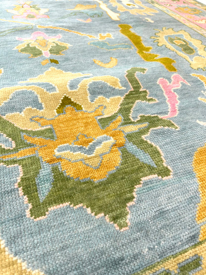 Addie Modern Oushak rug close-up, medium blue, pink border, green, orange, tan, cream, chartreuse-olive, hand-knotted 100% wool