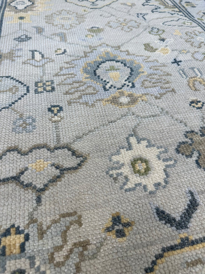 Margot modern Oushak rug with a gray center, light blue border, and mustard, green, cream, and navy accents, hand-knotted wool