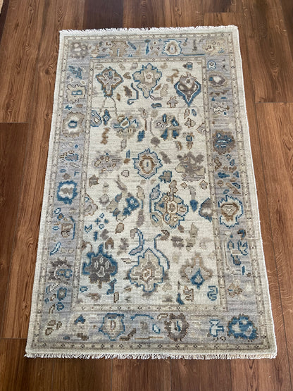 Ollie modern Oushak rug, cool gray with blue undertones, taupe border, and cobalt, cream, and brown accents