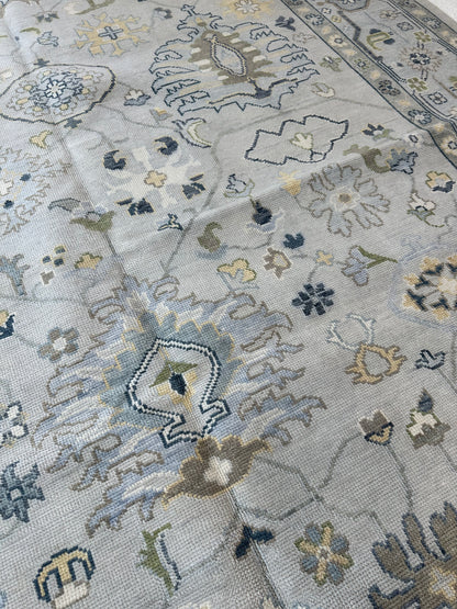 Margot modern Oushak rug with a gray center, light blue border, and mustard, green, cream, and navy accents, hand-knotted wool