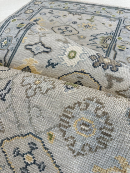 Margot modern Oushak rug with a gray center, light blue border, and mustard, green, cream, and navy accents, hand-knotted wool
