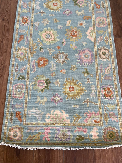 Gracie Modern Oushak rug styled in a room, blue-green, orange, pink, purple, green, tans, hand-knotted wool