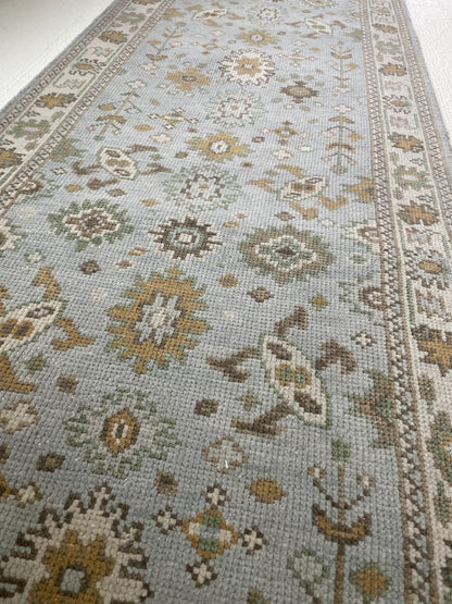 Katherine hand-knotted wool modern Oushak rug in light blue with cream, tan, ochre, and green