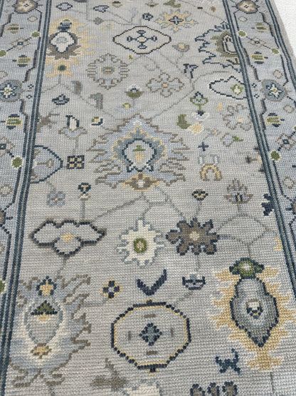 Margot hand-knotted wool modern Oushak rug in a gray center, light blue border, and mustard, green, cream, and navy accents